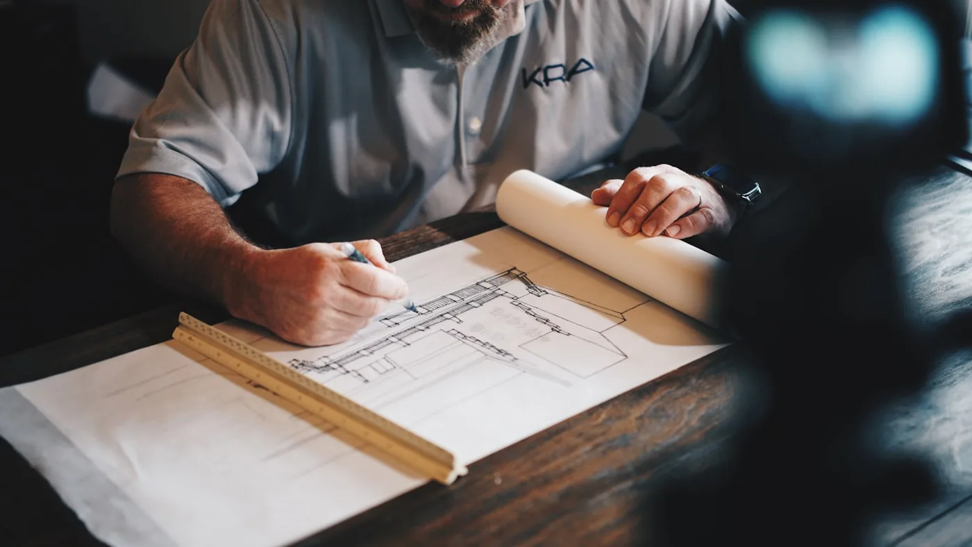 Contractor reviewing job costs and project plans at a workbench